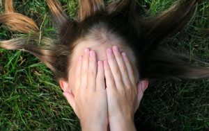 young teen girl covering her face